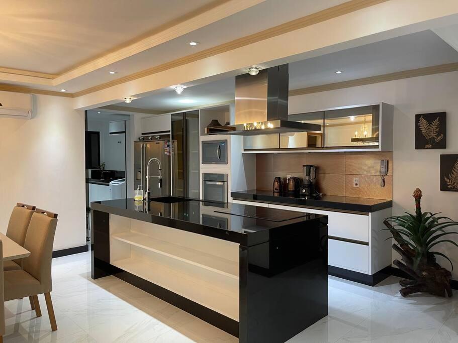 una cucina con piano di lavoro nero in una camera di Apartamento de luxo 3 quartos na Praia do Morro com vista para o mar a Guarapari