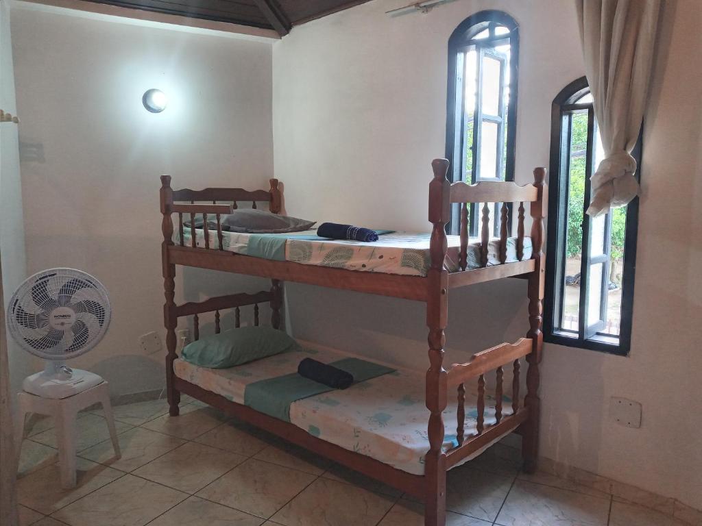 a room with two bunk beds and a fan at Calango's Beach-House-Arraial do Cabo in Arraial do Cabo