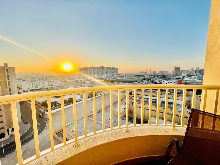 a view of a city from a balcony with the sunset at Stay at Al Ghaimah Holiday Homes 1 Bedroom Apartment Near Airport in Dubai