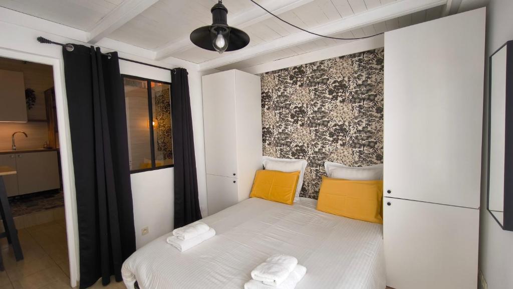 a small bedroom with a white bed and yellow pillows at L'Excursion - Charmant T2 Rénové proche de la mer in Cassis