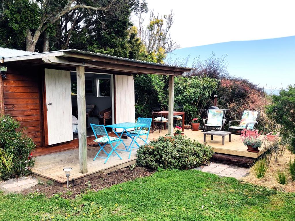 eine Hütte mit einem Tisch und Stühlen auf einer Terrasse in der Unterkunft Haumoana Herb Cottage in Haumoana