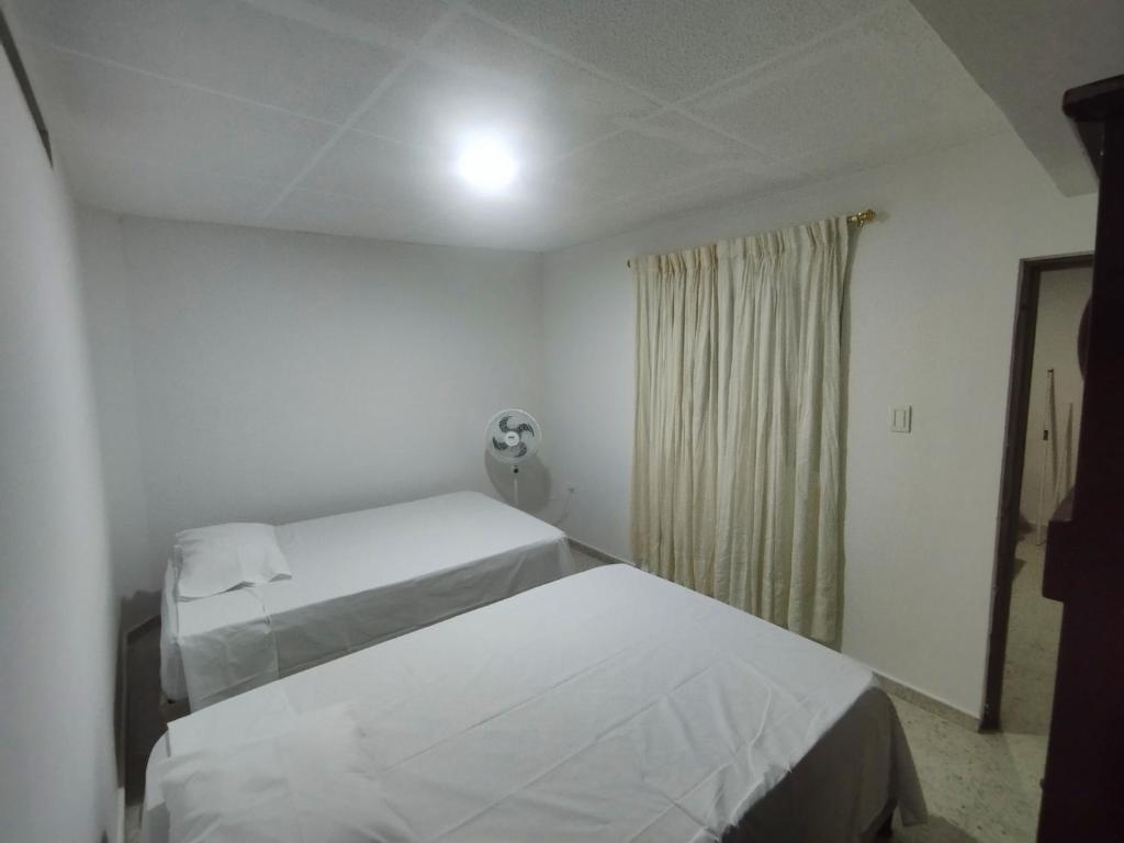 um quarto branco com 2 camas e uma janela em Hostal, casa Jaramillo em Roldanillo