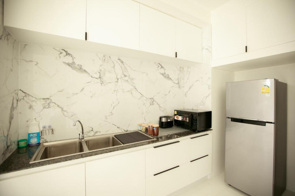 a white kitchen with a sink and a refrigerator at Lafami Hostel in Ban Nongdouang