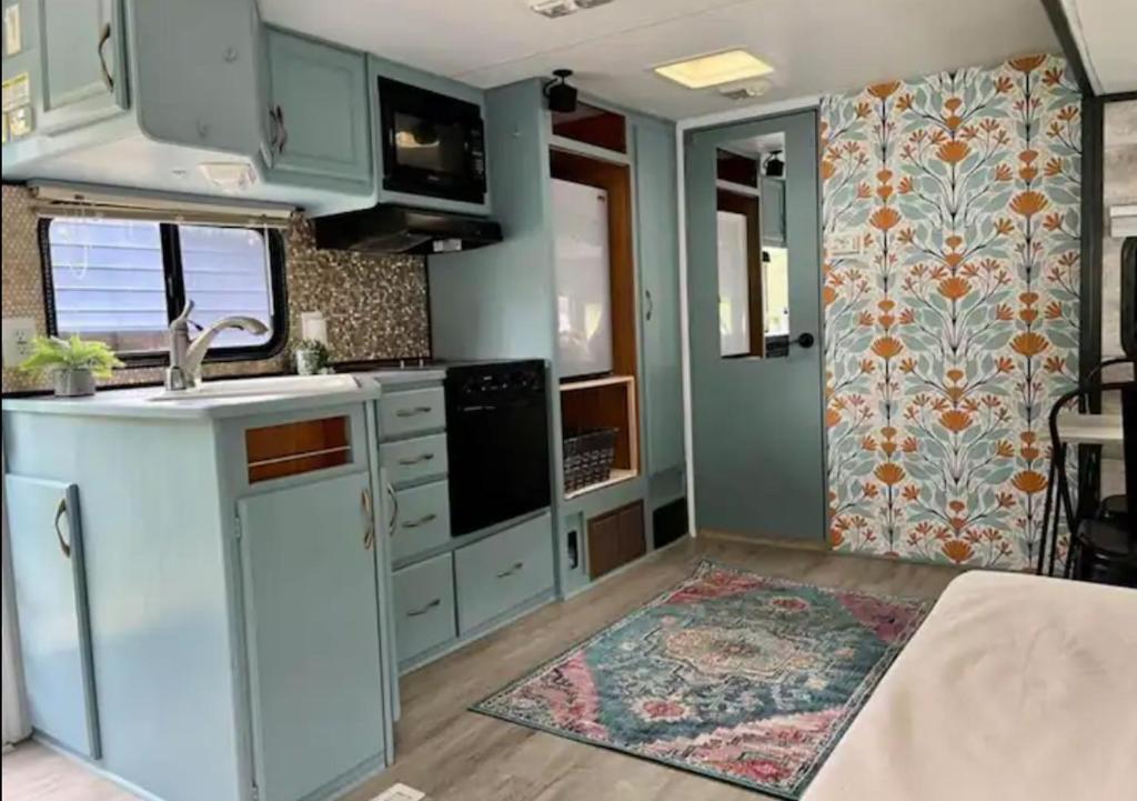 una cucina con mobili blu e tappeto di Happy Camper - Close to Mackinac Island a Carp Lake