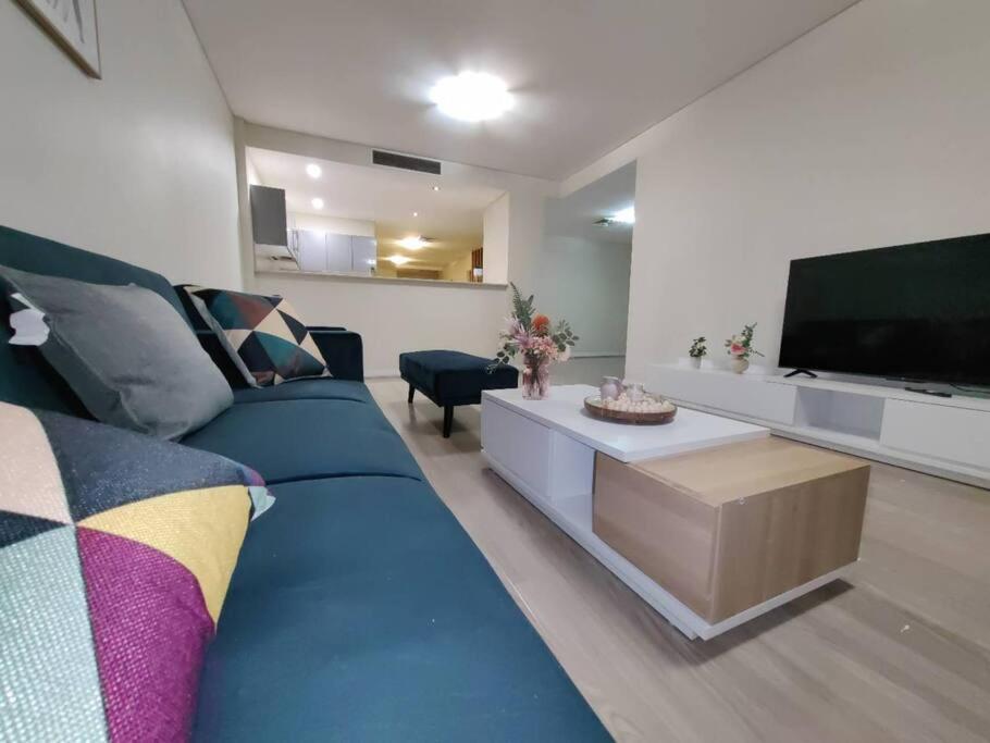 a living room with a blue couch and a tv at Entire 3 bed apartment in Ryde in Sydney