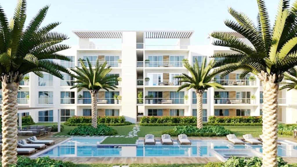 an apartment building with palm trees and a swimming pool at Vibe Residence Dominicus in Bayahibe