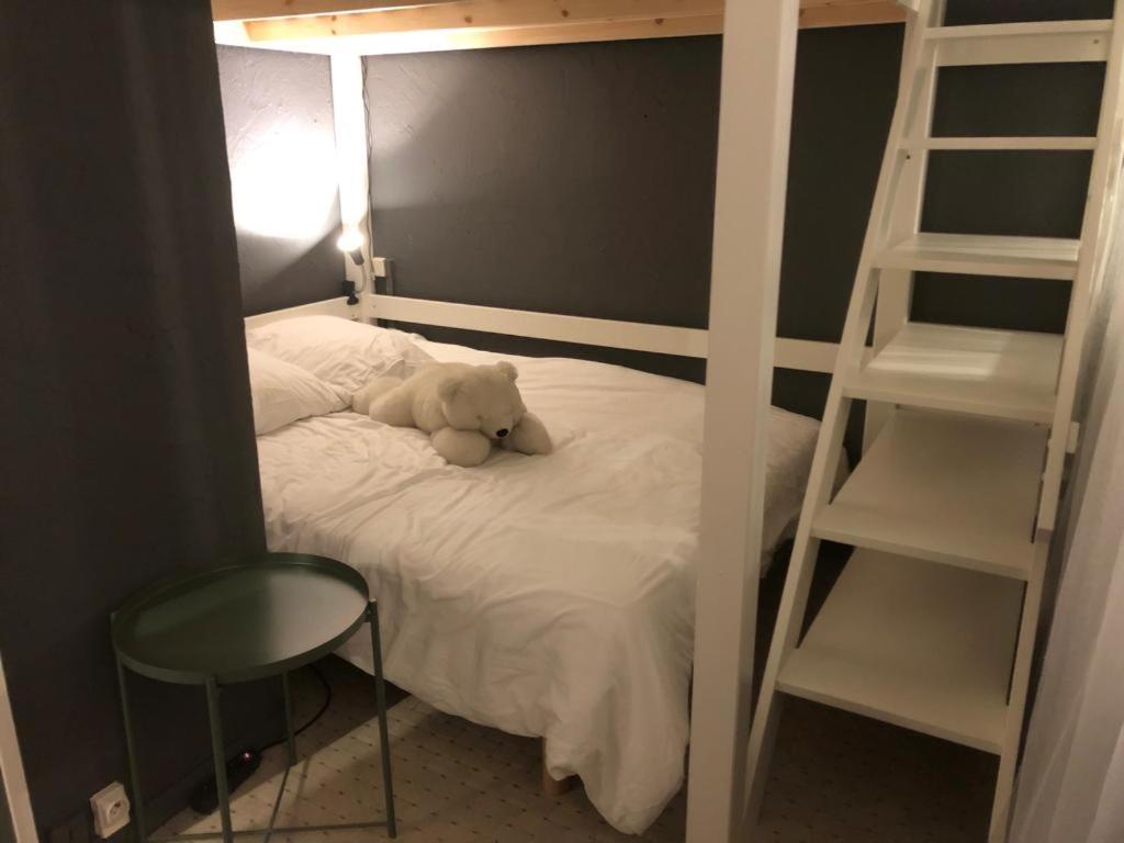 un oso de peluche sentado en una cama con una escalera en Appartement au pied des pistes, en La Plagne