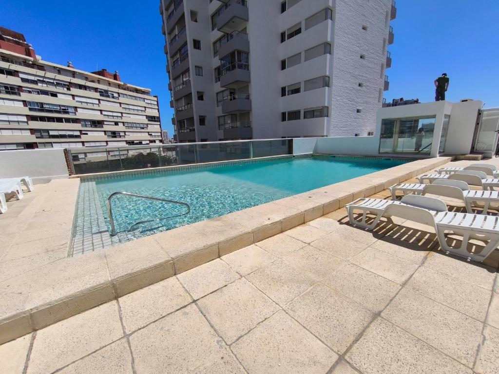 a swimming pool with chairs and a building at Apto 3 dormitorios, Punta del Este parada 2 in Punta del Este