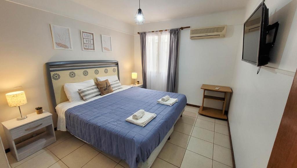 1 dormitorio con 1 cama azul y 2 toallas en La Quinta departamento en Mendoza