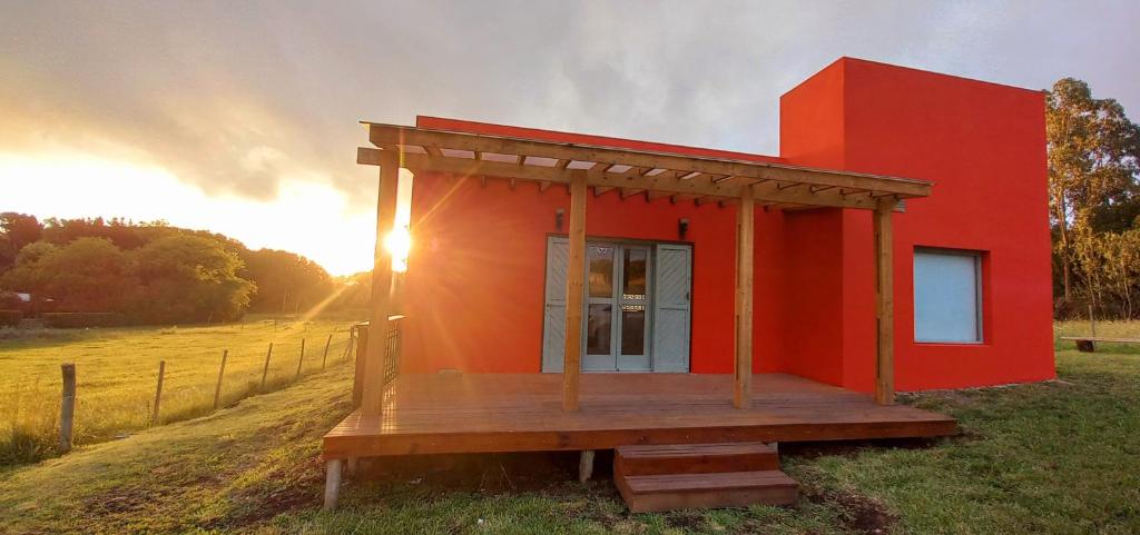 a small red house with a deck in a field at Casa Rose Chapadmalal in Mar del Plata