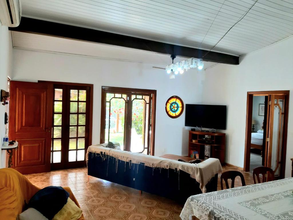 uma sala de estar com uma cama e uma televisão em Casa ÍSIS de aluguel por temporada em Capão da Canoa com piscina em Capão da Canoa