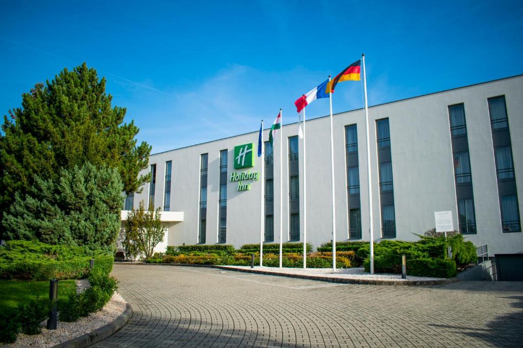 a building with two flags in front of it at Holiday Inn Budapest-Budaörs, an IHG Hotel in Budaörs