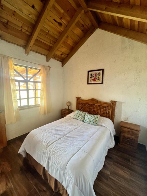 Schlafzimmer mit einem großen weißen Bett und einem Fenster in der Unterkunft Cabañas el Corral del Rayo Huasca in Huasca de Ocampo