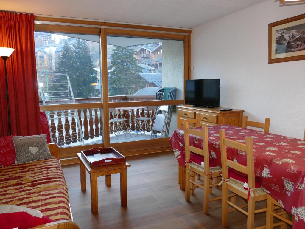 d'un salon avec une table et une télévision ainsi que d'un balcon. dans l'établissement Grand Appartement aux Deux Alpes - 6 Pers, 2 Ch, Balcon - Proche des Pistes - FR-1-546-29, à Les Deux Alpes