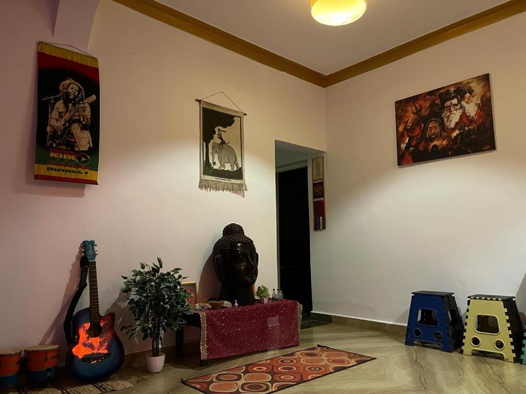 ein Wohnzimmer mit einem Zimmer mit einer Gitarre und ein Zimmer mit in der Unterkunft 4BHK Private Farm House for Budget Group stay in Mandrem