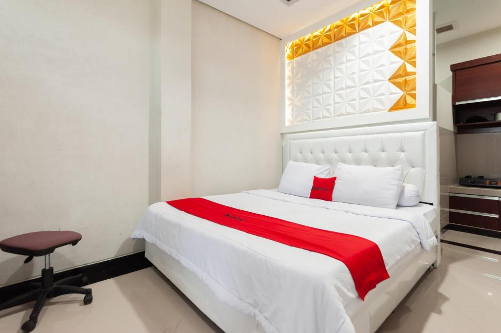 a bedroom with a large white bed and a chair at RedDoorz Syariah near Pasar Aceh Shopping Centre in Banda Aceh