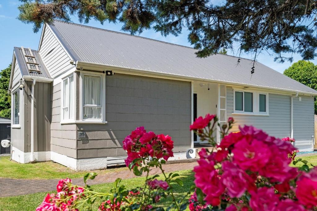 a small house with pink flowers in front of it at Whare 35 - Rotorua Holiday Home in Rotorua