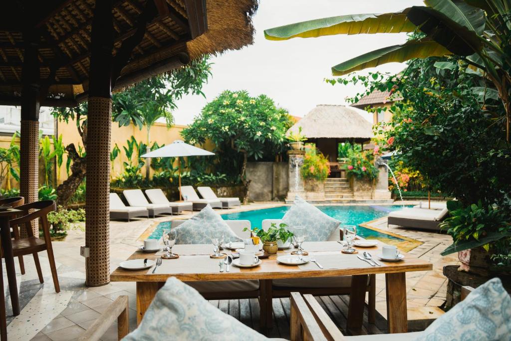a patio with a table and chairs next to a pool at Sri Phala Resort & Villa in Sanur