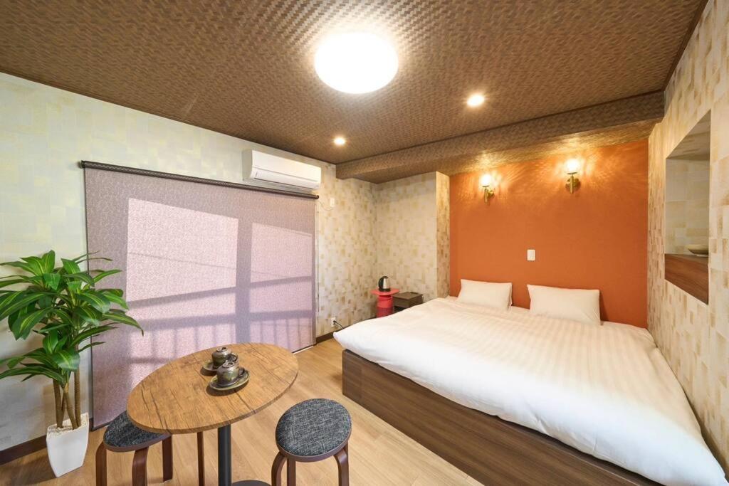 ein Schlafzimmer mit einem großen Bett und einem Tisch in der Unterkunft ホテル八広 in Tokio