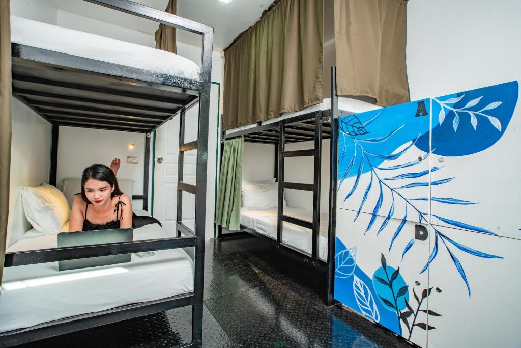 a woman sitting in a bed in a bunk bed room at LArtista Hostel in Puerto Princesa City