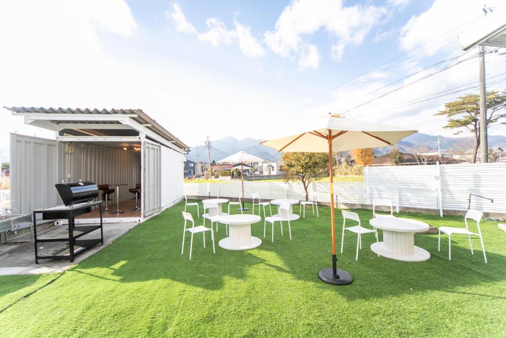 un patio con tavoli, sedie e ombrellone di 菰野ガーデンリゾート 