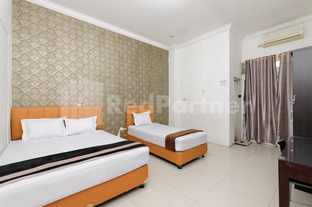 a bedroom with two beds and a tv at RedDoorz at Wisma Nabila Banda Aceh in Banda Aceh