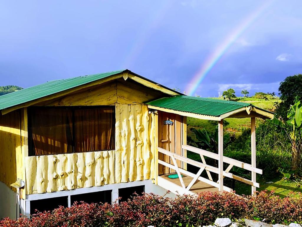 a wooden house with a green roof and a rainbow in the background at Hotel Cotobruseño 