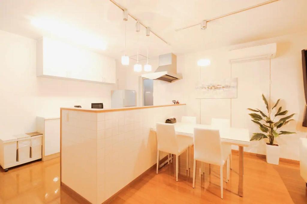 a white kitchen with a table and chairs at ファミリア・デザインハウス札幌 in Sapporo