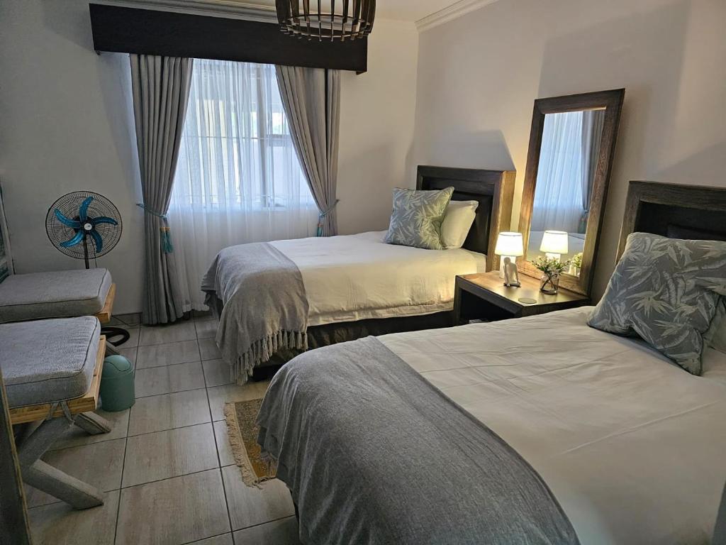 una habitación de hotel con 2 camas y una silla en Déjàvu at the Bay, en Richards Bay