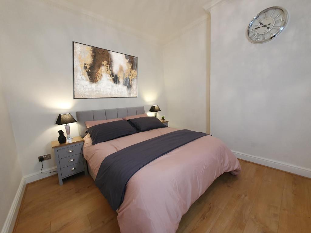1 dormitorio con 1 cama grande y reloj en la pared en Hyde Park Elegance Escape : Central & Cozy, en Londres