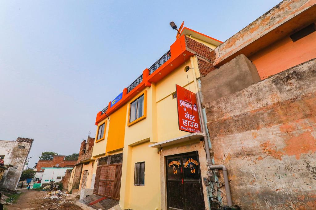 een geel en oranje gebouw met een bord erop bij FabExpress Hanuman Ji in Ayodhya