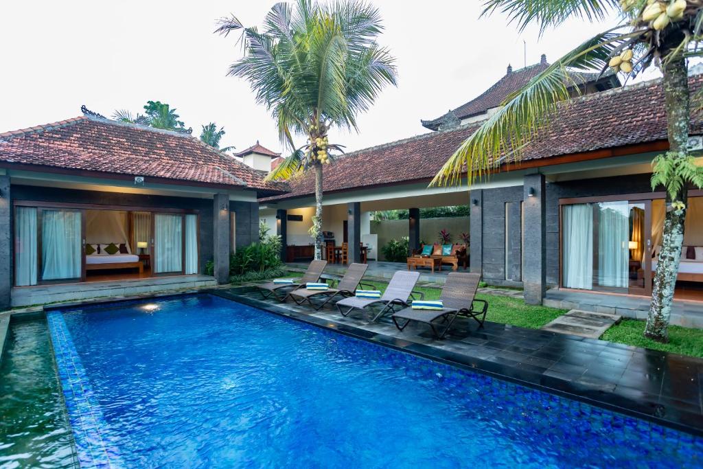a swimming pool with two chairs and a house at Ubud Heaven Sayan in Ubud