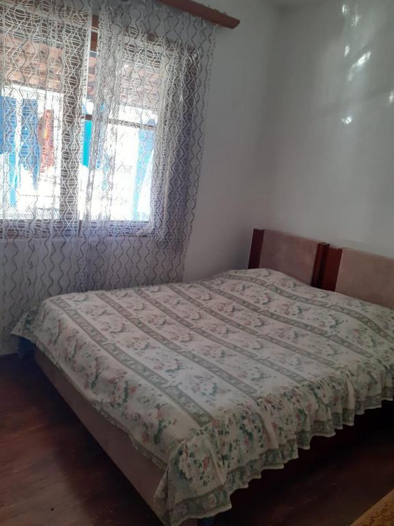 ein Schlafzimmer mit einem Bett und zwei Fenstern in der Unterkunft Hana Private Home in Pogradec