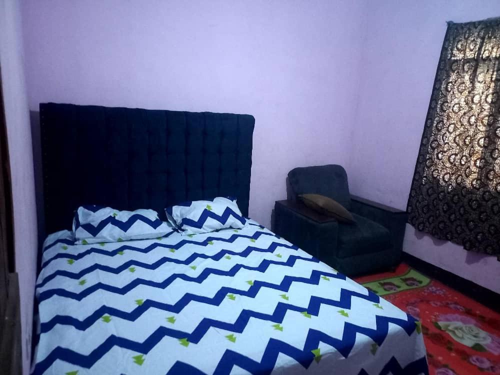 um quarto com uma cama azul e branca e uma cadeira em Bright Backpackers home stay em Mwanza