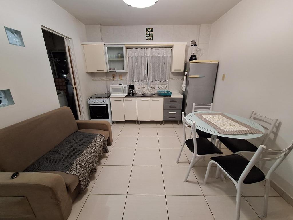 a living room with a couch and a table and a kitchen at Cantinho da Ro in Balneário Camboriú