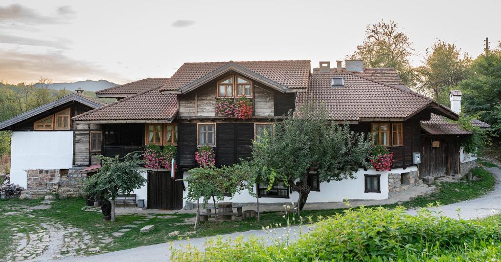 une vieille maison en bois avec des fleurs sur les fenêtres dans l'établissement Kandaphery Guest Houses, à Miykovtsi