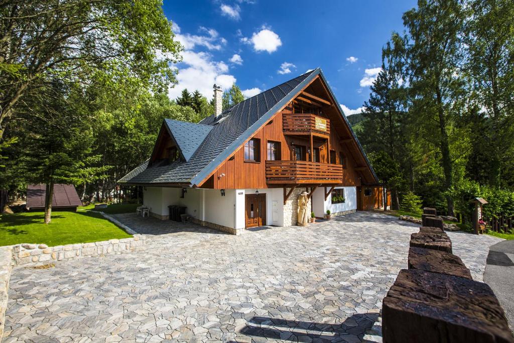 uma casa com um telhado de gambrel numa entrada de pedra em Apartmány Slunce em Harrachov