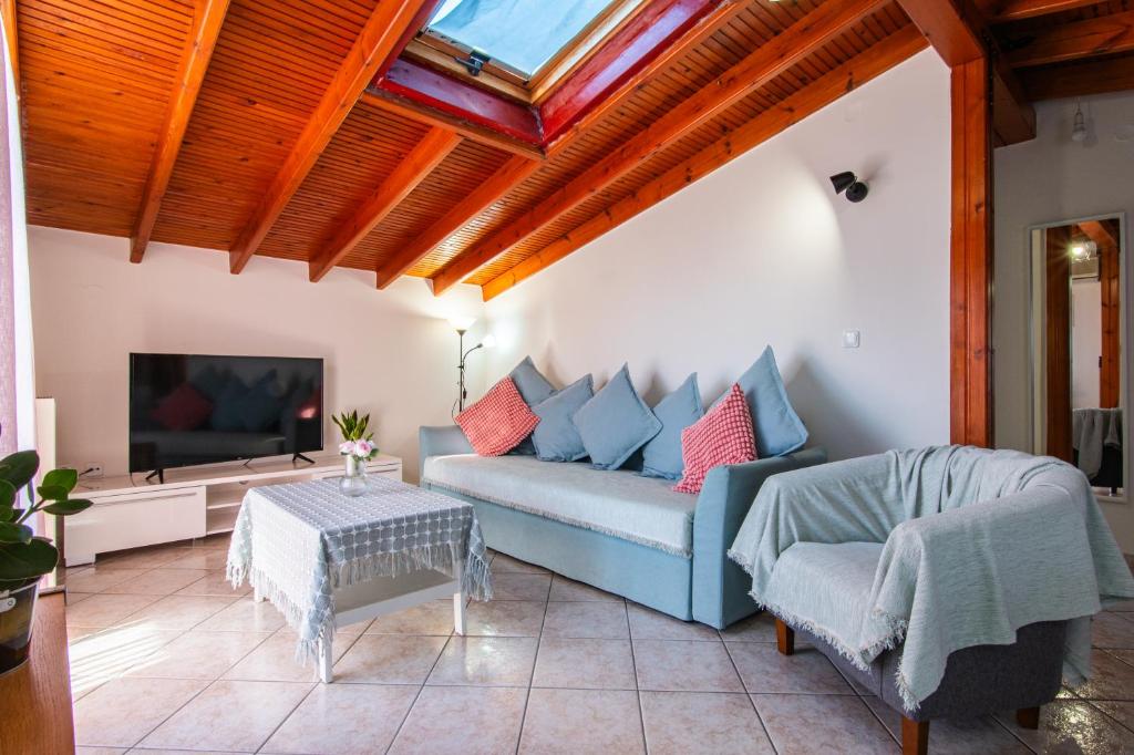 un soggiorno con divano blu e TV di Sunset rooftop apartment a Salonicco