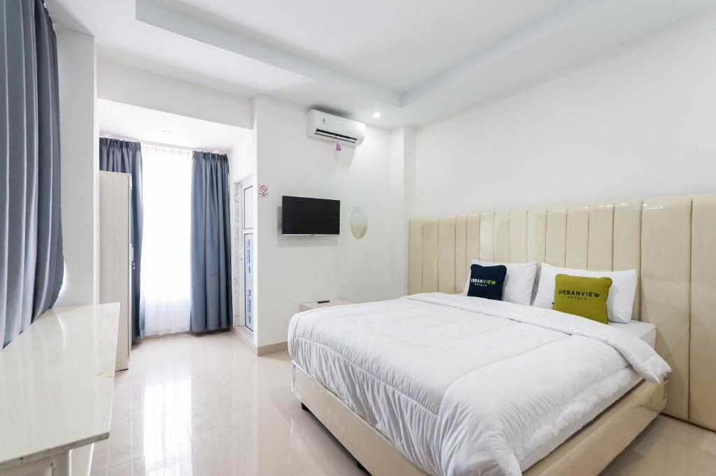 um quarto branco com uma cama grande e uma televisão em Urbanview Hotel Ranls Dream Banda Aceh by RedDoorz em Banda Aceh