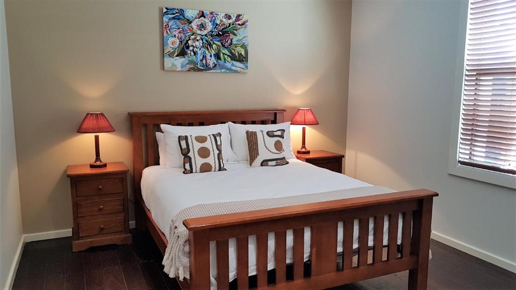 1 dormitorio con 1 cama de madera y 2 lámparas en Kangaroo Island Seabright Garden Cottage, en Kingscote