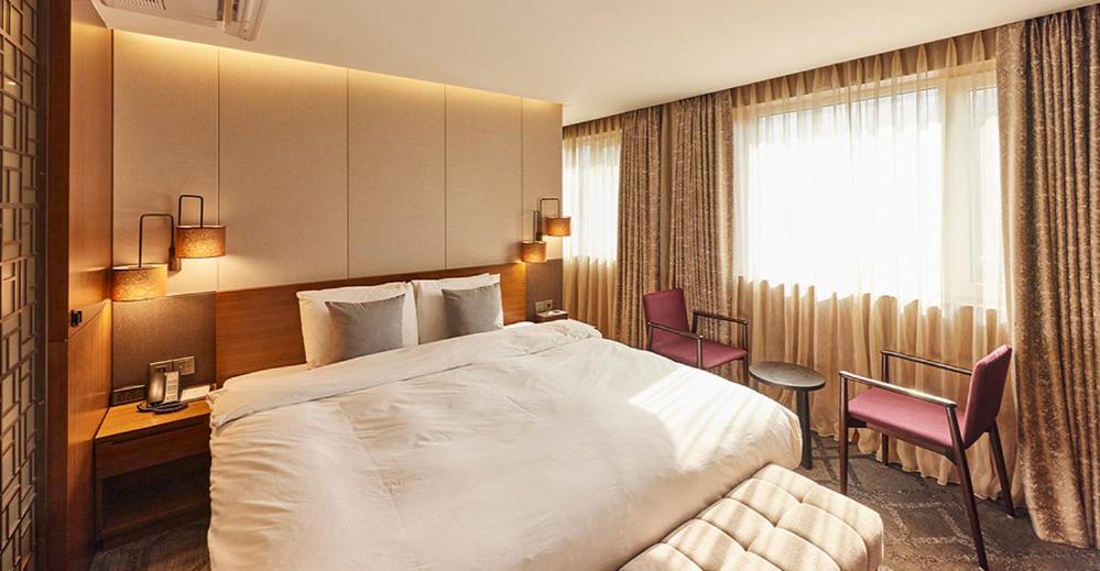 ソウルにあるHotel Uri&のベッド、テーブル、椅子が備わるホテルルームです。