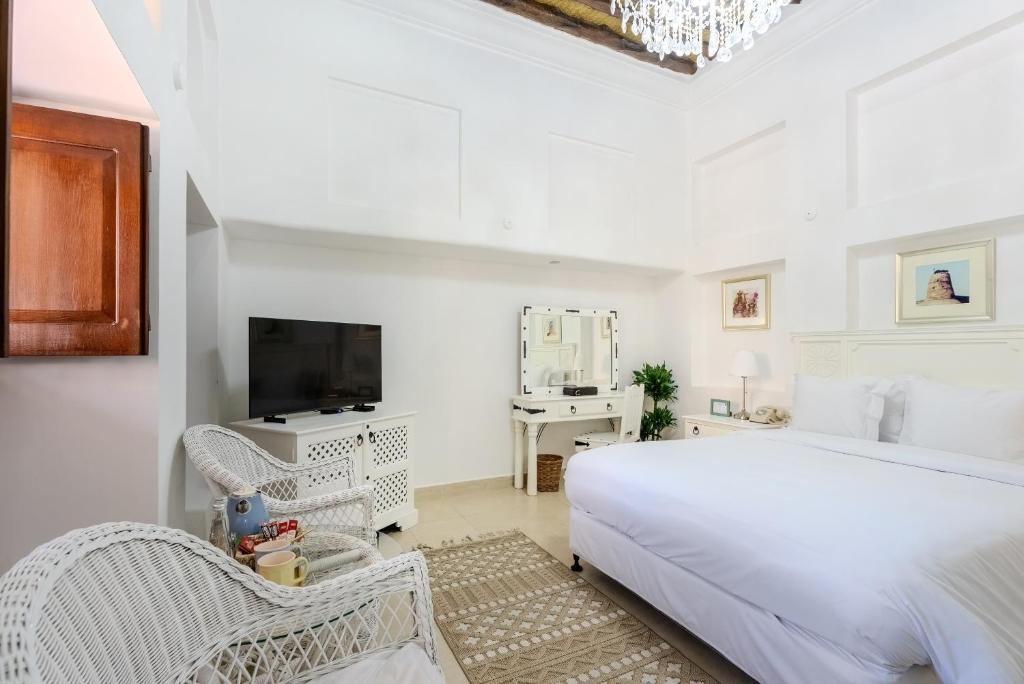 a white bedroom with a bed and a tv at Arabian Boutique Hotel in Dubai