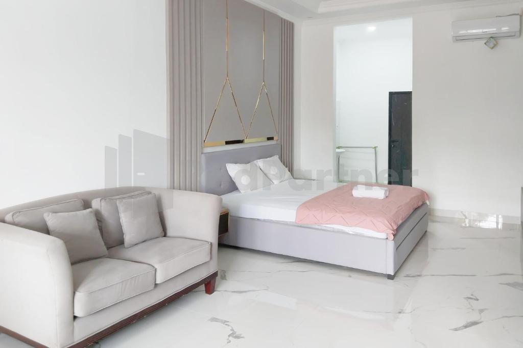 a white bedroom with a bed and a couch at Khayrizsan Premium Mitra RedDoorz in Cibeureum
