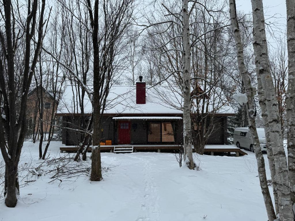 ein Haus mit einem roten Hydranten auf dem Dach im Schnee in der Unterkunft 美瑛森林木屋 - 小紅帽 in Biei