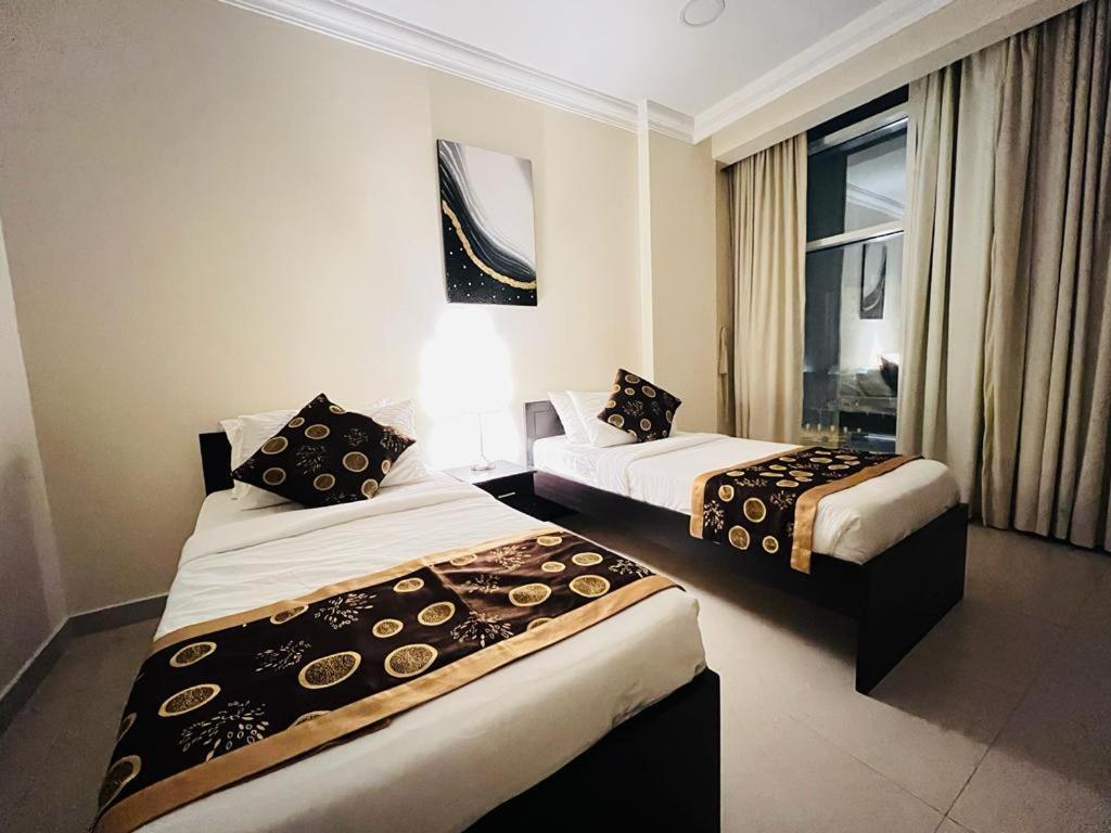 um quarto de hotel com duas camas e uma janela em Chelsea Gardens Apartment em Doha