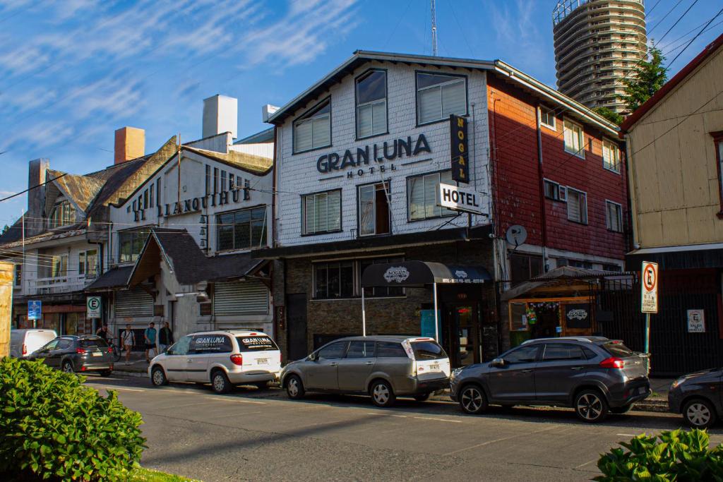 una strada di città con auto parcheggiate di fronte agli edifici di Hotel Gran Luna a Puerto Montt