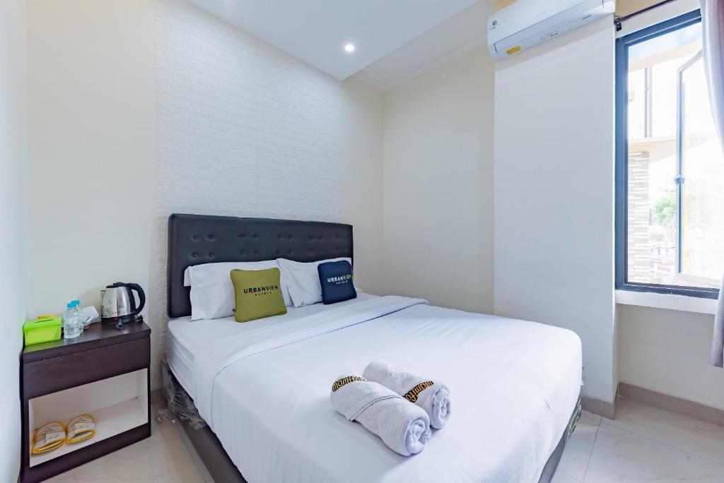 a white bedroom with a bed with towels on it at Urbanview Hotel Mamifokobo Puncak in Sindanglaya
