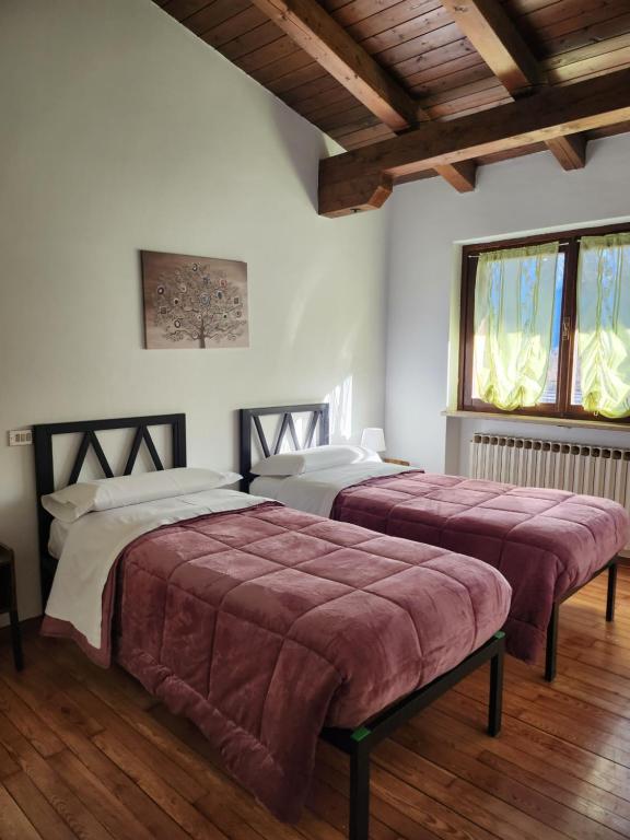 2 camas num quarto com pisos e janelas em madeira em Margiolà em Calalzo