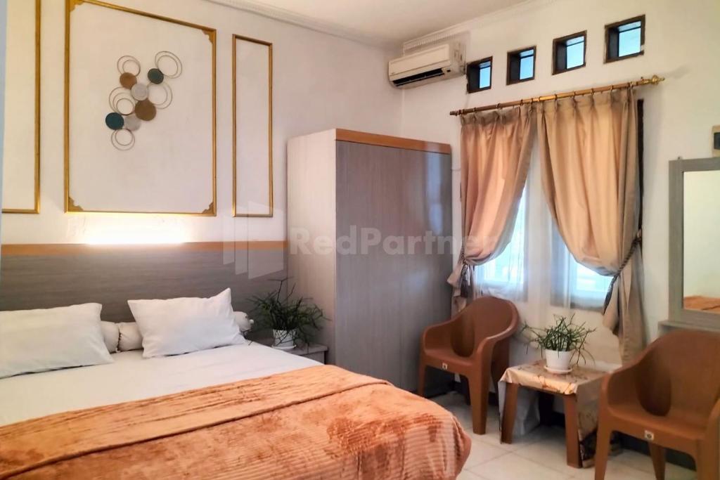 1 Schlafzimmer mit einem Bett, 2 Stühlen und einem Fenster in der Unterkunft Rosa Luxury Jagakarsa RedPartner in Jakarta