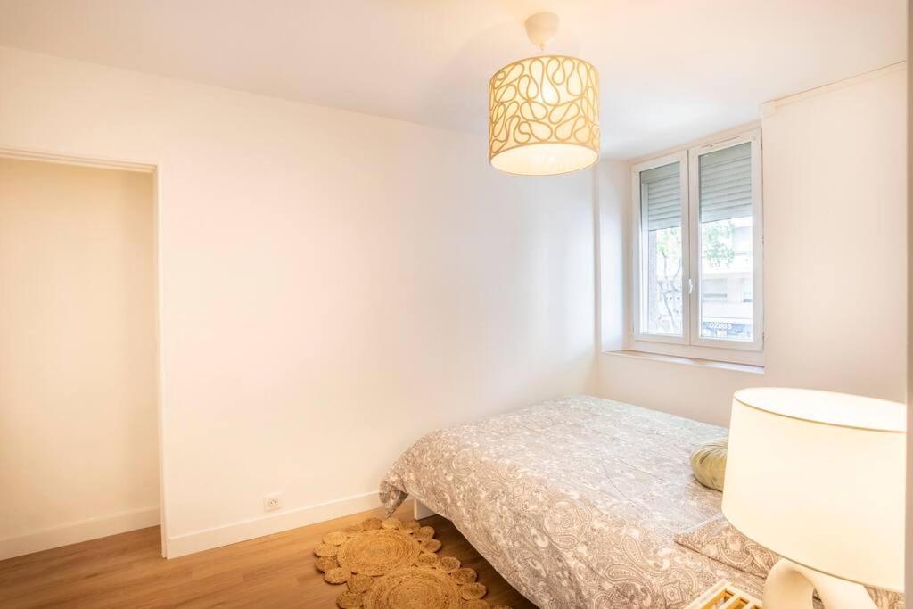 a white bedroom with a bed and a window at Le nid de la Corderie in Marseille